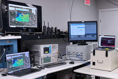 RFCO test bench — spectrum analyzer, signal generators, shielded enclosures and laptops running 3D RF scenario displays
