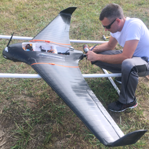 Aspen operator preparing a black flying-wing UAV in the field